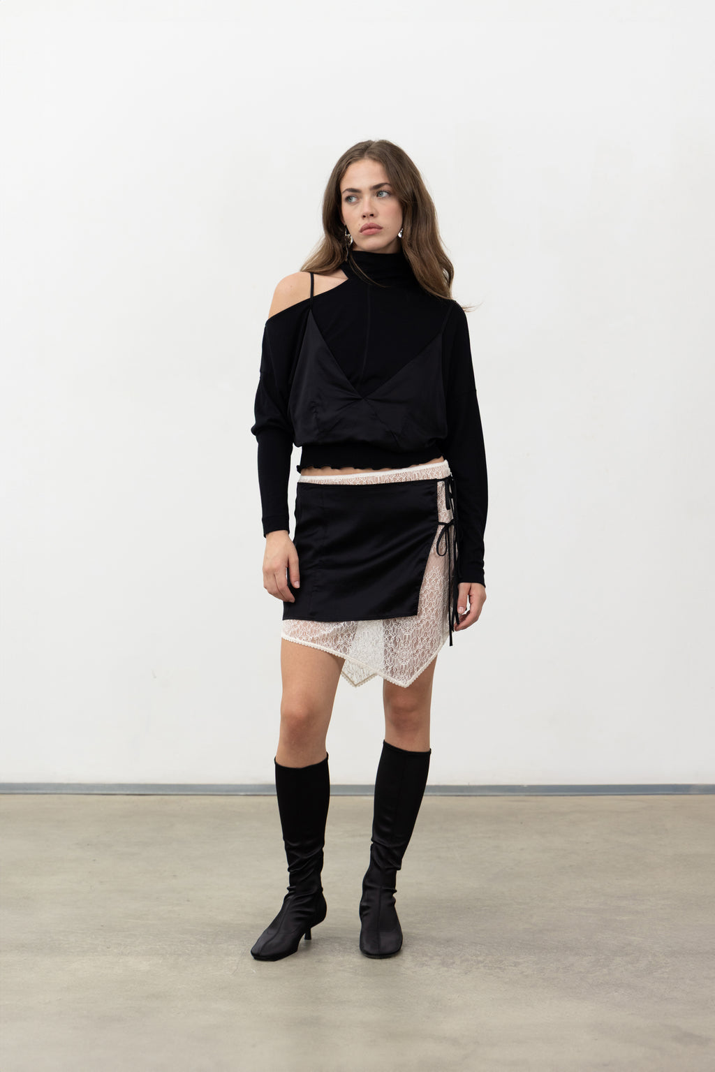 Full-length view of the black Doppia mini skirt with the Sacro Top and boots