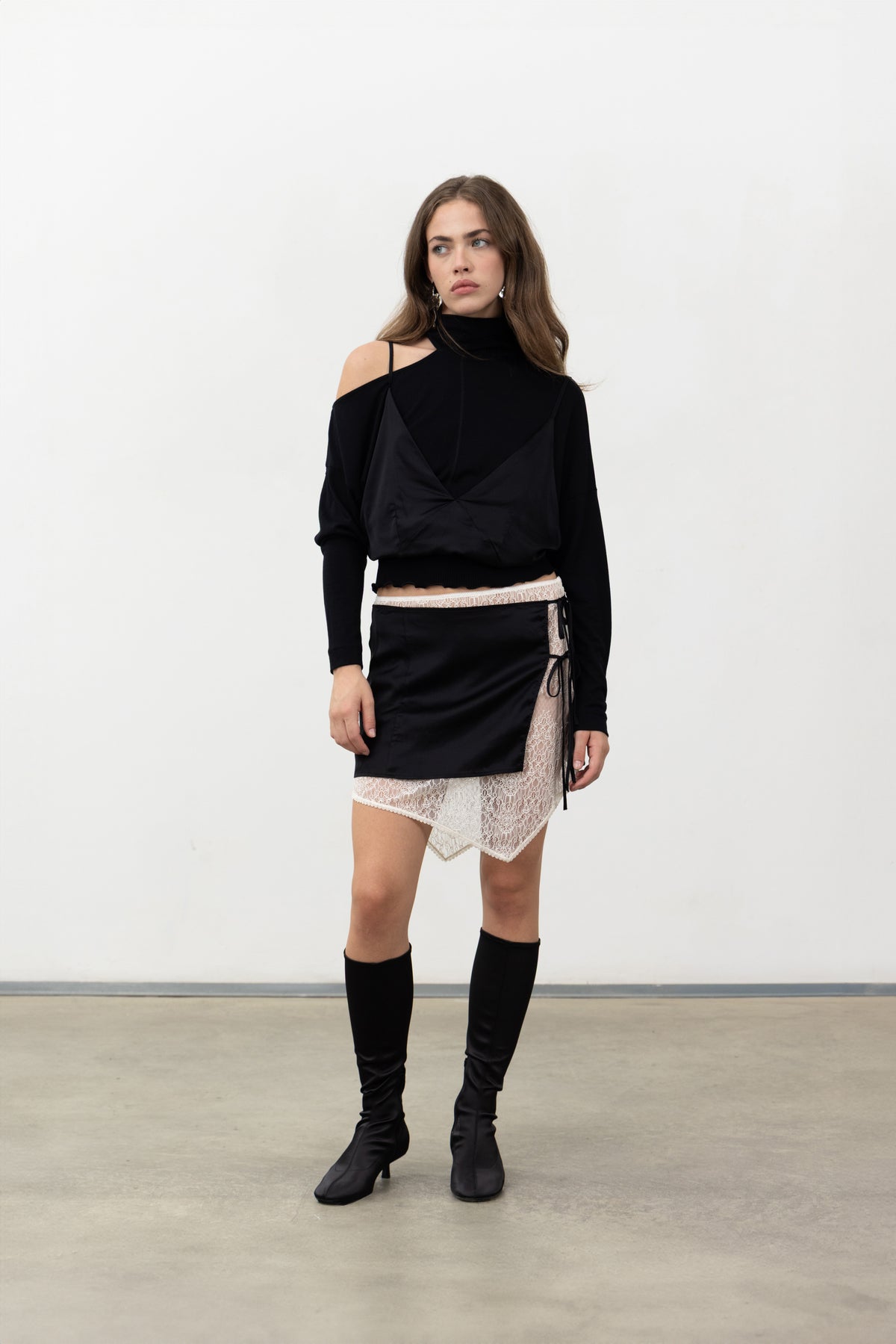 Full-length view of the black Doppia mini skirt with the Sacro Top and boots