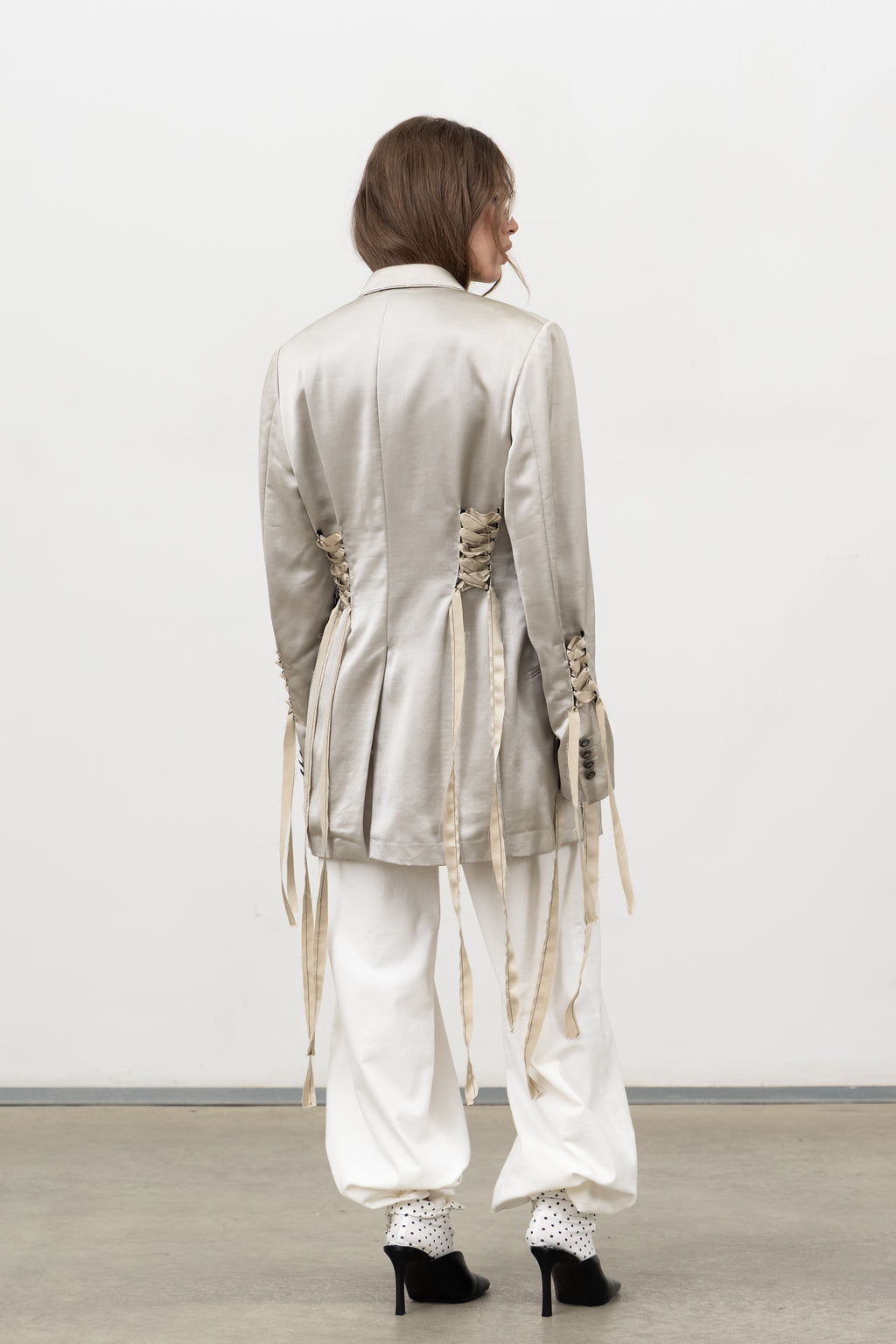 Back view of the Sacro Blazer, a one-of-a-kind champagne satin blazer with corset lacing and long ribbons