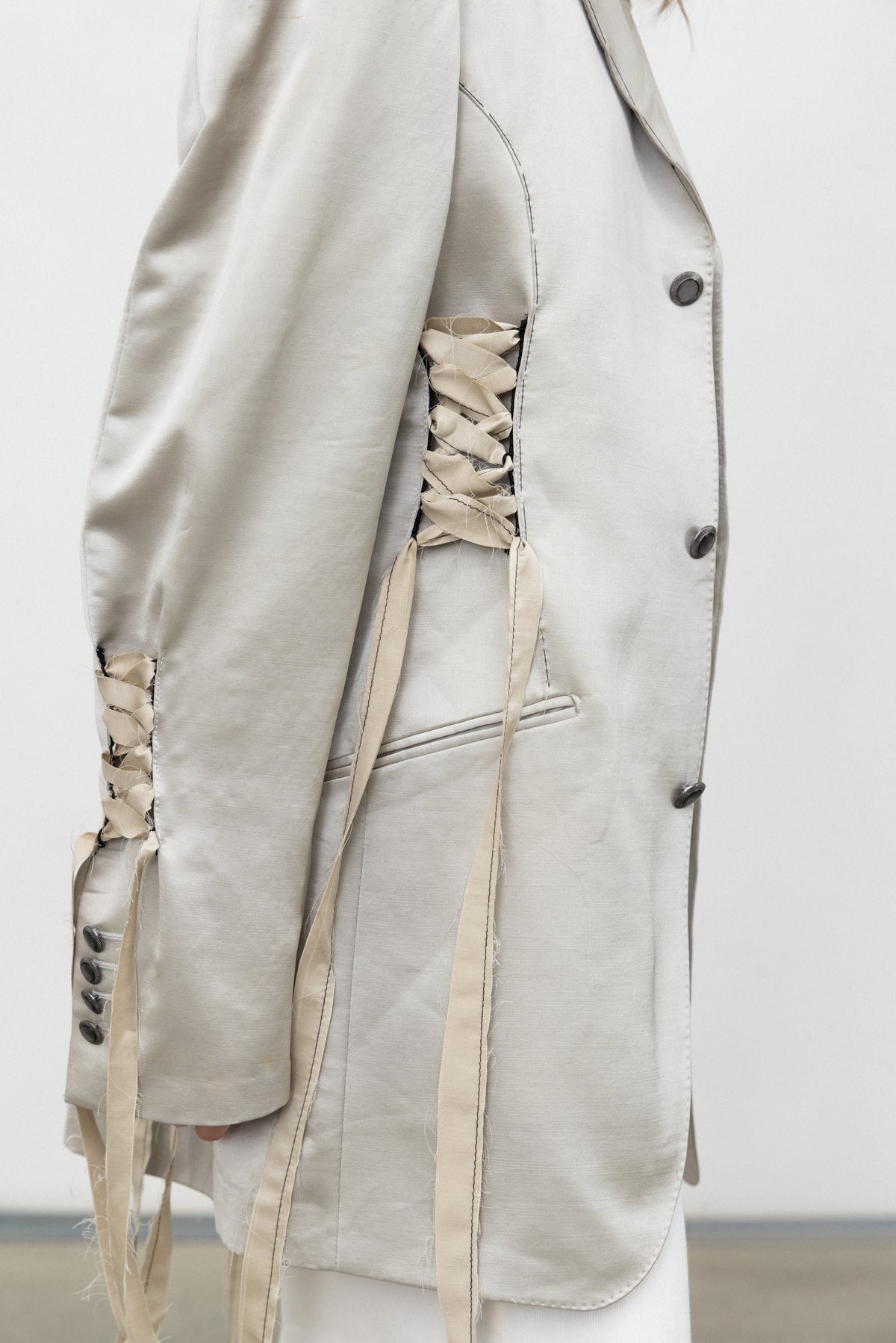 Detail of the corset-inspired lacing at the side and sleeve of the Sacro Blazer