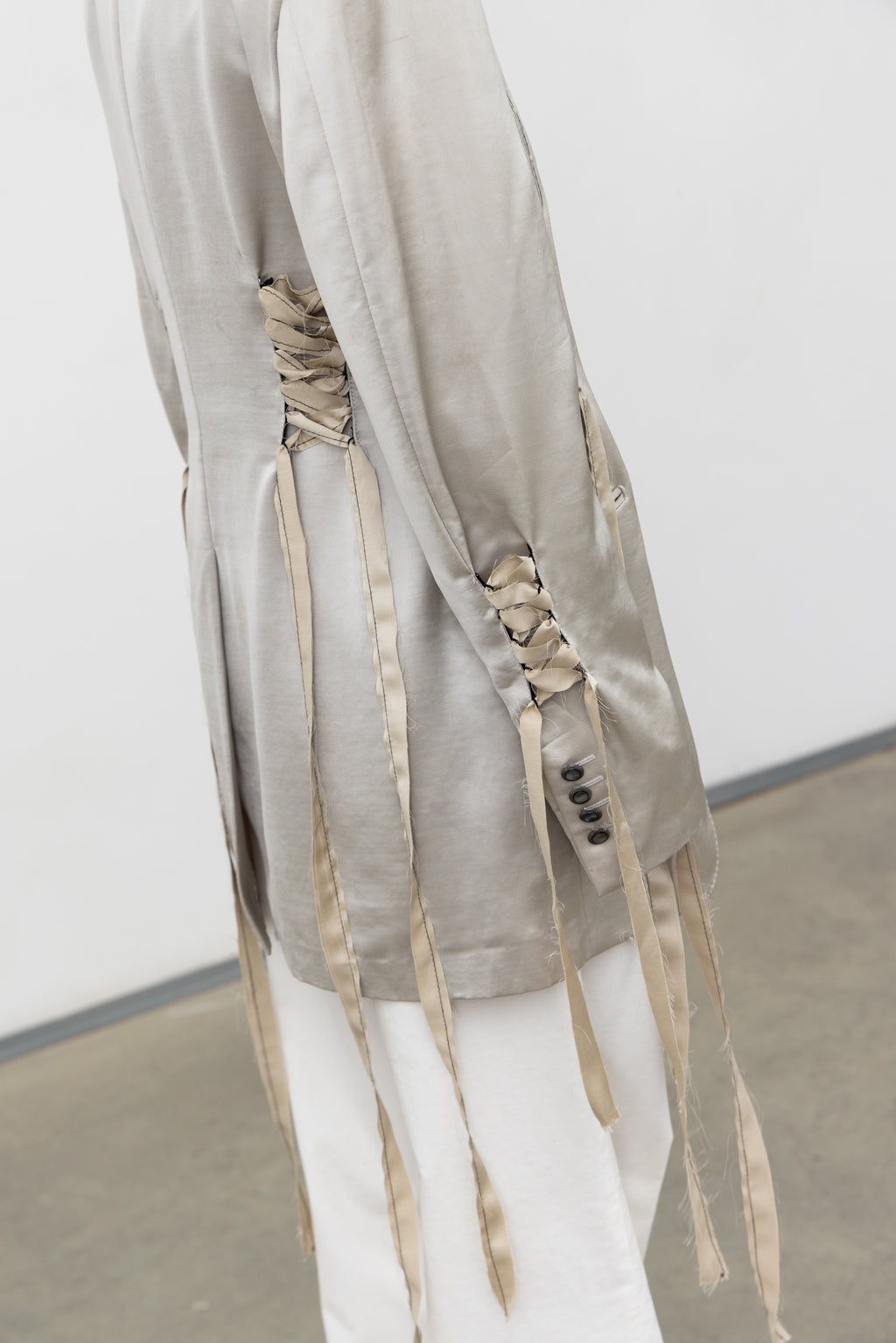 Detail of the eyelet lacing and flowing ribbons on the sleeve of the Sacro Blazer