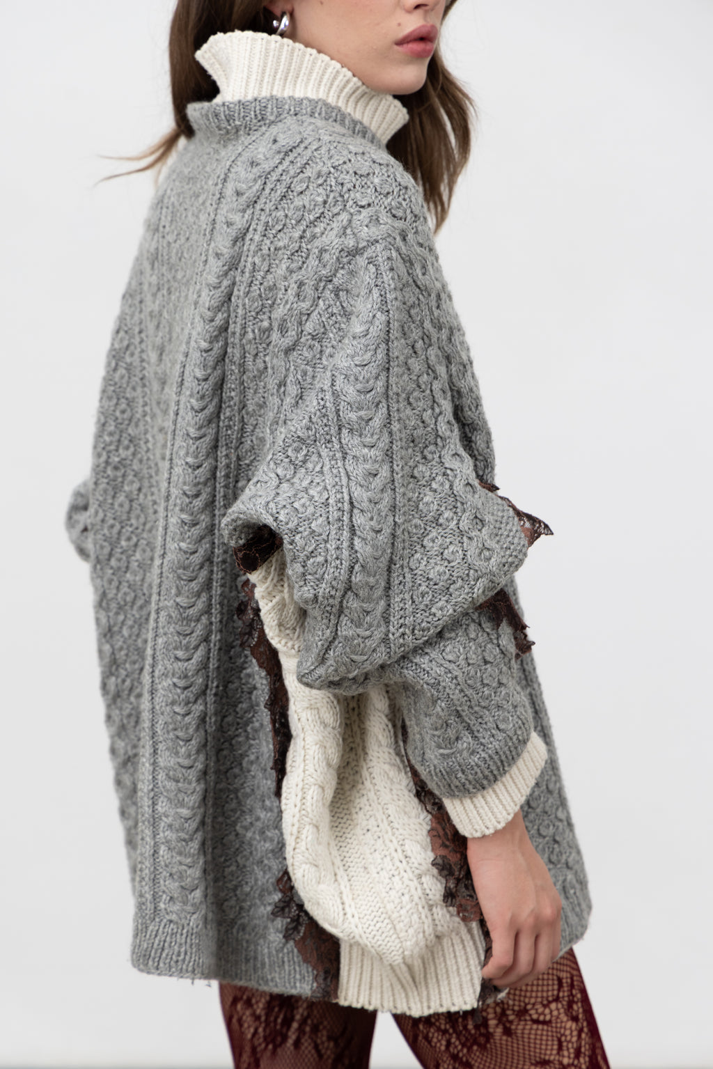 Side view of the Dimenticato Cardigan joined from grey and ivory cable-knit sweaters