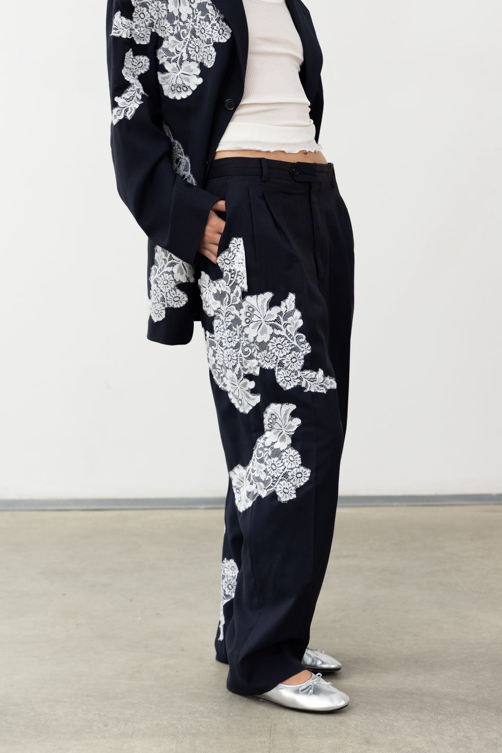 Detail of the white lace across the thigh of the Allegoria navy wool trousers