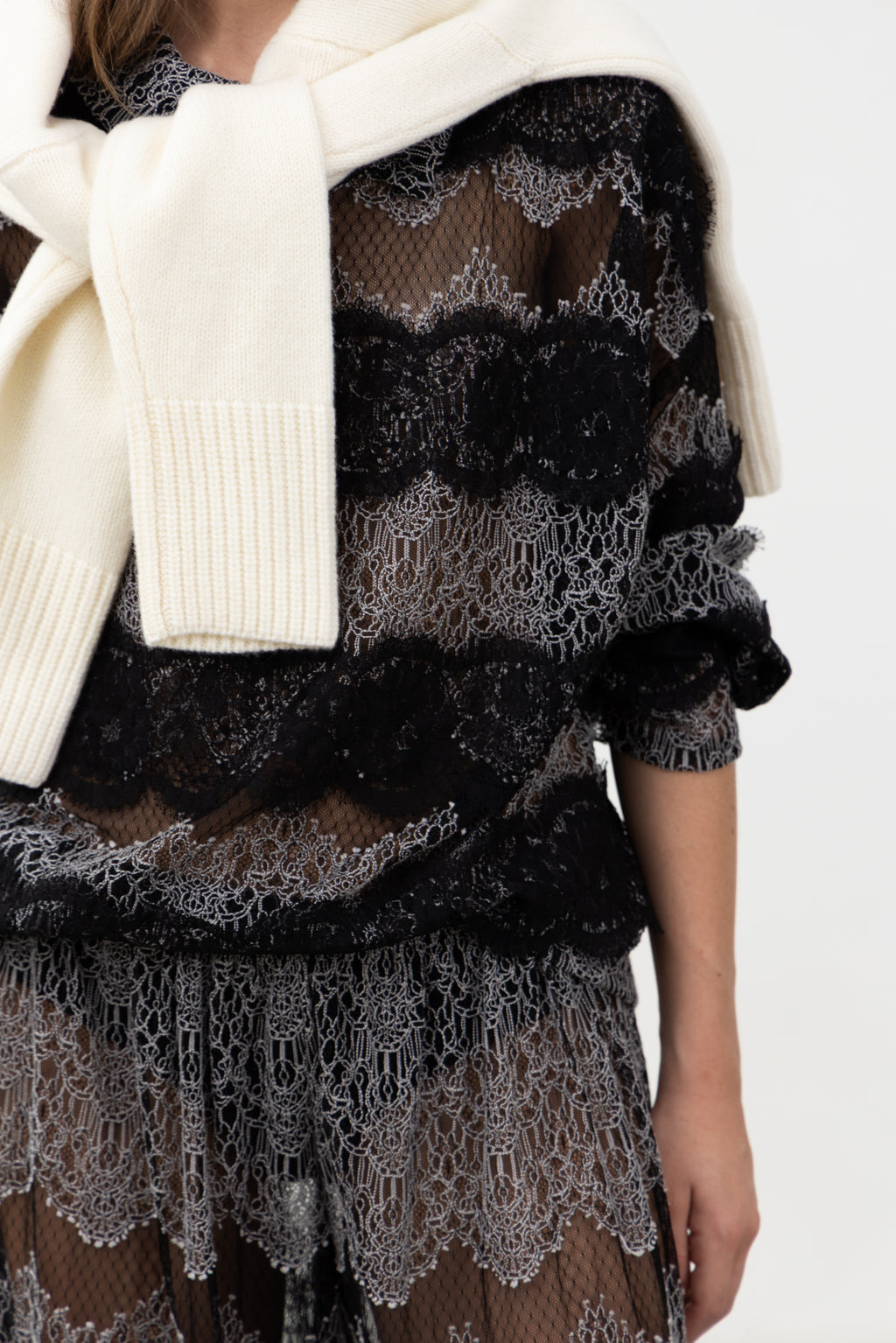 Close-up of the black lace bands on the Sbagliato Dark Top, styled with a cream knit over the shoulders