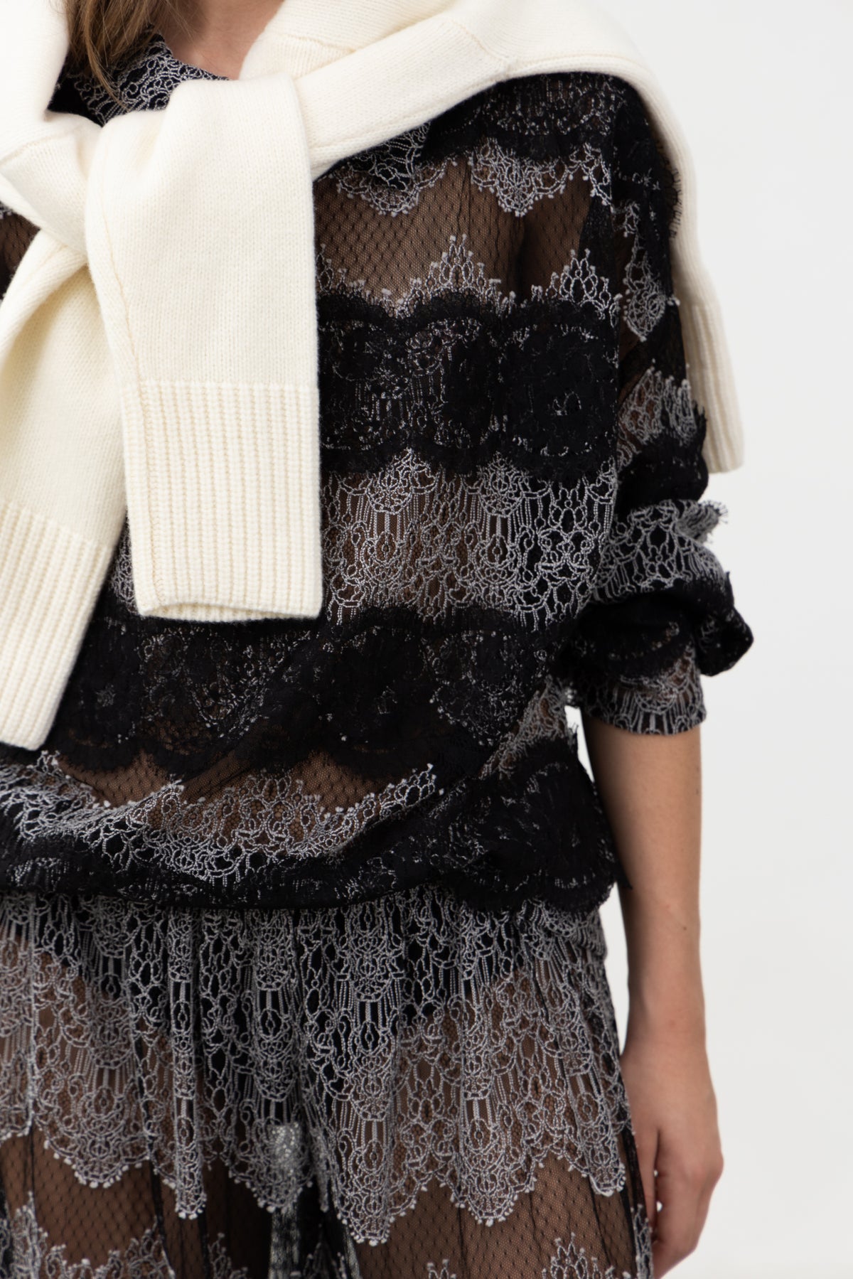 Close-up of the black lace bands on the Sbagliato Dark Top, styled with a cream knit over the shoulders