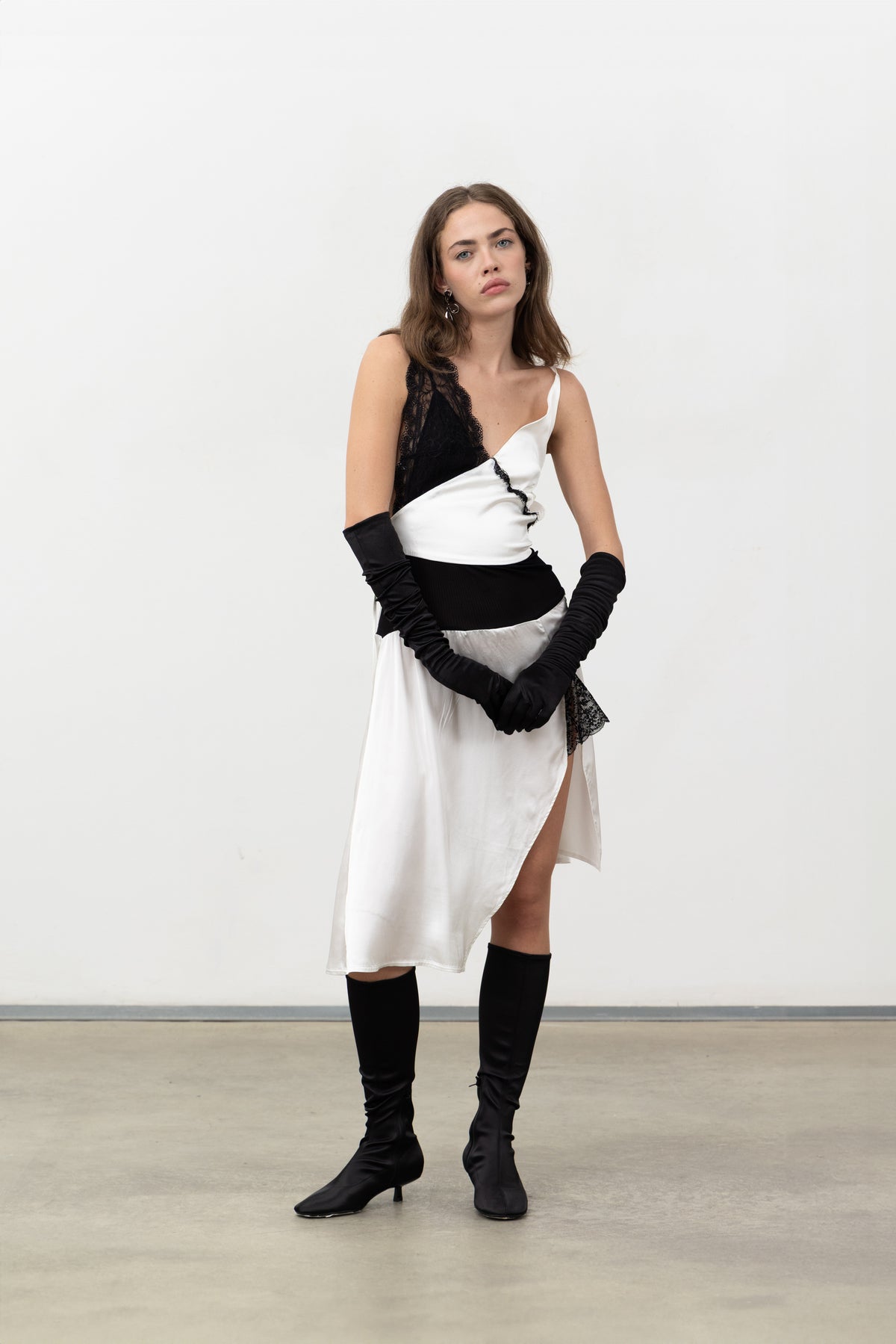 Full-length view of the Sacro Dress styled with black opera gloves and knee-high boots